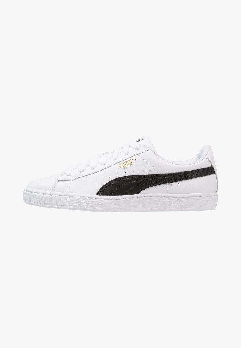 Baskets basses blanches avec détail de bande noire, fermeture à lacets et semelle texturée, vues de côté sur fond blanc.