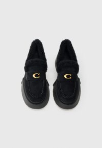 Juodi zomšiniai bateliai be kulno su puriu juodu pamušalu, apvaliu priekiu ir gumine pada. Auksinės spalvos detalė ant dirželio. Siuvinėtas dizainas visame paviršiuje.