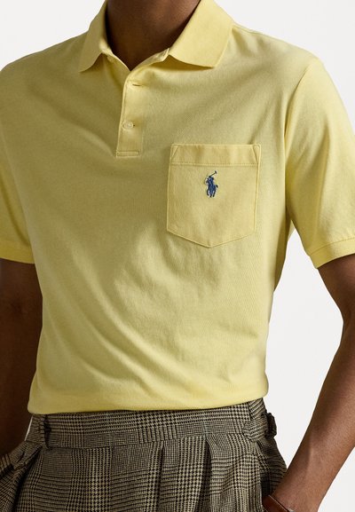 Pehmeast kollasest puuvillast polo särk klassikalise kraega, kahe nööbiga pael ja rinna tasku, millel on bluu värvi broderi logo.