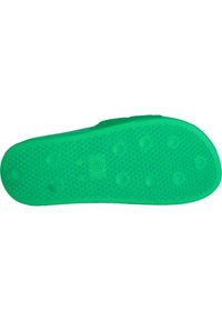 Groene rubberen zool met een textuur oppervlak, voorzien van cirkelvormige en driehoekige patronen en verhoogde bultjes voor grip.