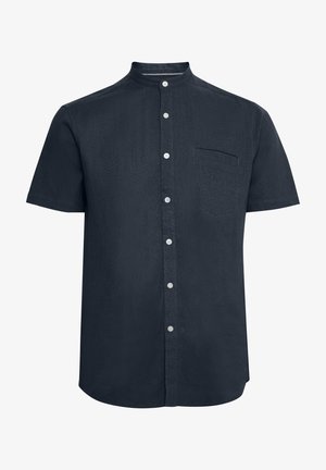 Camicia a maniche corte di un blu navy scuro, con colletto rialzato, cinque bottoni bianchi e taschino sul petto; tessuto strutturato.
