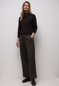 Donkerbruin coltrui met een slanke pasvorm en lange mouwen, gecombineerd met hooggetailleerde, wide-leg grijze broek met steekzakken aan de voorkant en een subtiele textuur.