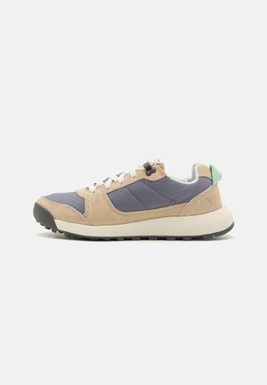 Sneakers mają beżową zamszową cholewkę oraz niebieskie syntetyczne elementy, białe sznurówki, jasnozielony uchwyt na pięcie i masywną czarną gumową podeszwę.