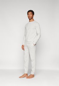 Top de manga larga gris claro y pantalones a juego, hechos de material suave, con cuello redondo y puños elásticos en los tobillos.