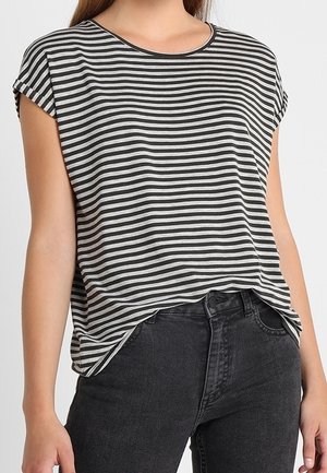 Vrouw met een zwart-wit horizontaal gestreept T-shirt met korte mouwen, lichtjes ingestopt in een hooggetailleerde zwarte spijkerbroek.