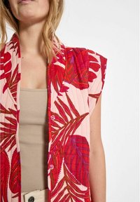 Prešívaný kimono v ružovej farbe s jasne červenými a fialovými listovými vzormi. Má rukávy s krátkym strihom a gombíky pozdĺž prednej strany. Mäkčená textúrovaná tkanina.