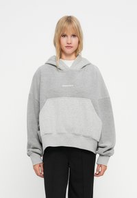 Pilkas per didelis hoodie, pagamintas iš minkštos medvilnės mišinio, su priekyje esančia kengūros kišene ir gumbuotomis rankovėmis, ant krūtinės yra "PEGADOR" logotipas.