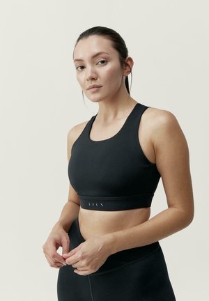 Svart trenings-BH med scooped halsutskjæring og brede stropper. Den har en tettsittende silhuett og en jevn, stretchy tekstur med subtil merking.