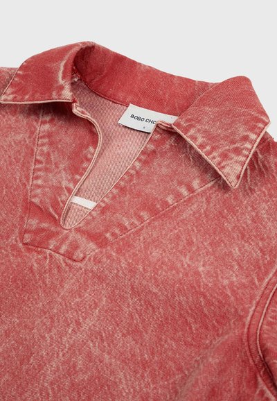 Rode acid-wash denim shirt met kraag, v-halsopening en zichtbaar merklabel aan de binnenkant van de halslijn.