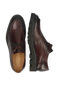 Brązowe skórzane eleganckie buty z gładkim wykończeniem, zaokrąglonym noskiem i grubą czarną gumową podeszwą. Posiadają wiązanie na sznurowadła oraz przeszycia ozdobne.