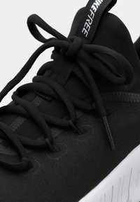 Μαύρο αθλητικό παπούτσι με υφασμάτινο άνω μέρος, υφή στην επιφάνεια, παχύ λευκό πέλμα και στρογγυλά κορδόνια με σχέδιο βρόχου.