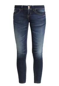 Jeans de mezclilla de corte Slim en azul oscuro con parches desgastados. Cuenta con cinco bolsillos, cierre de botón y cremallera, y detalles de costura.