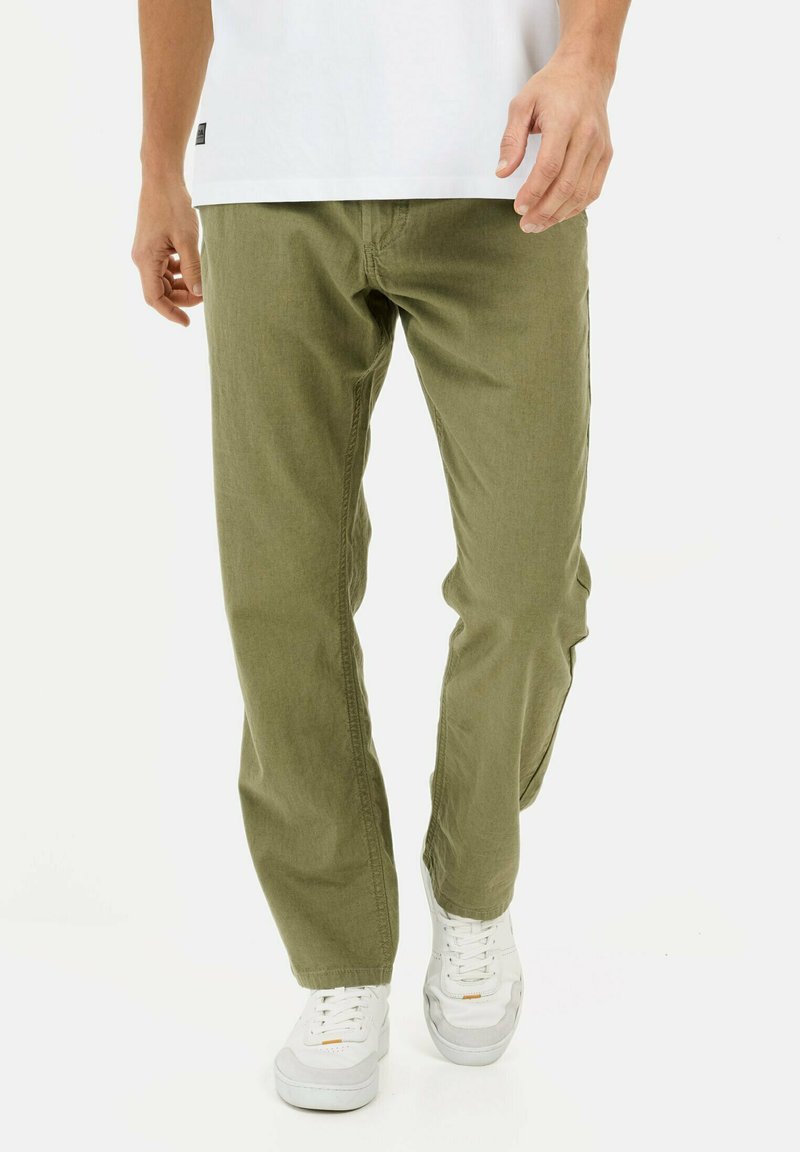 Olivenfarvede bukser med lige ben, lavet af bomuldsstof. Kombineret med hvide sneakers, der viser en afslappet stil og komfort.