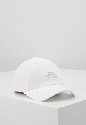 Witte honkbalpet met gebogen klep die op een wit oppervlak ligt, met een subtiel geborduurd "The North Face" logo aan de voorkant.