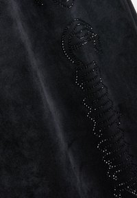 Zwart suède stof met een uniek ontwerp, verfraaid met kleine zwarte rhinestones, waardoor een textuur- en reflecterende oppervlakte ontstaat.