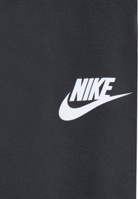 Schwarzer Nike-Stoff mit glatter Textur, der ein auffälliges weißes Nike-Logo und Swoosh-Design zeigt.