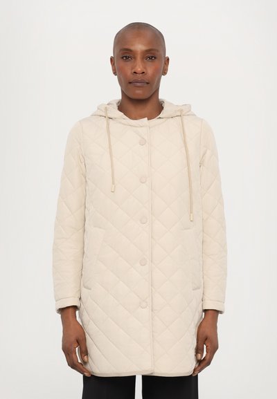Manteau matelassé beige avec capuche, présentant une fermeture à boutons-pression, deux poches latérales et des cordons de serrage ajustables sur la capuche.