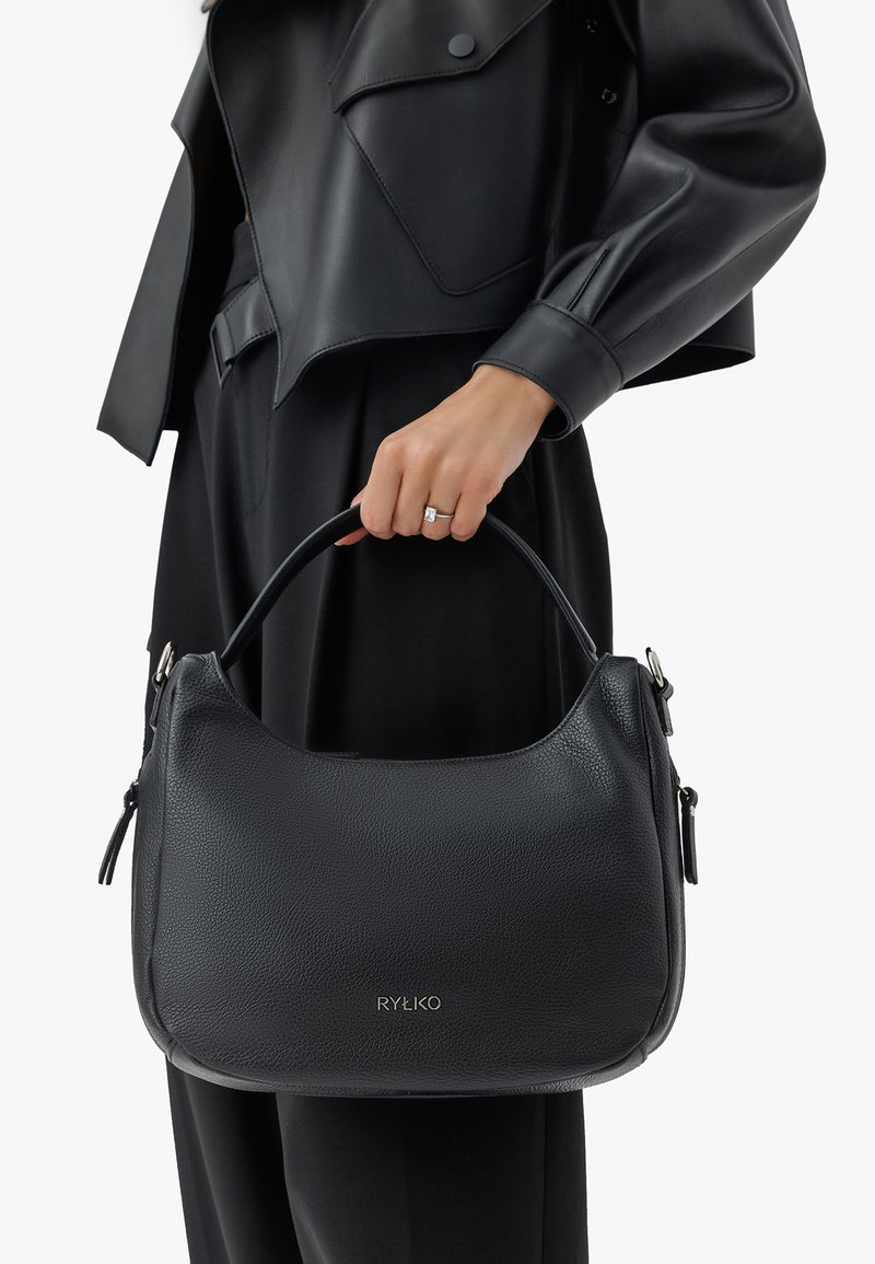 Sac à main en cuir noir avec une finition texturée, une forme courbée et une anse supérieure. Comprend une fermeture à glissière en métal argenté et un logo gravé.