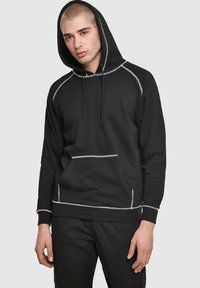 Melnas kapuces džemperis ar pelēkām šuvēm, priekšējo kabatu un ribām apkaltiem aprocēm. Izgatavots no mīksta materiāla, ar brīva piegriezuma un regulējamiem aukliņām.