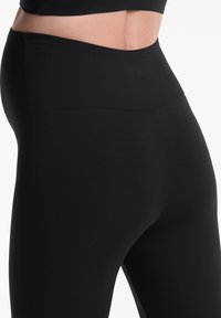 Fekete leggings sima, rugalmas anyagból és magas derekú gumiból. Minimális varrási részletek és karcsú sziluett jellemzi. Nincs látható logó.