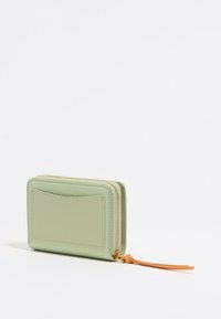 Portafoglio in pelle verde con finitura texture, chiusura a zip, tasca frontale per carte e linguetta di apertura arancione. Forma rettangolare.