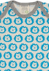 Weißer Baumwollstoff mit sich wiederholenden blauen Löwenköpfen und hellblauen Mähnen. Grauer gerippter Ausschnitt. Größenetikett: 74/80. Umweltfreundliche Zertifizierung.