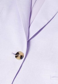 Blazer violet clair avec un seul bouton marron marbré près du revers et une petite poche avant sur le côté droit.