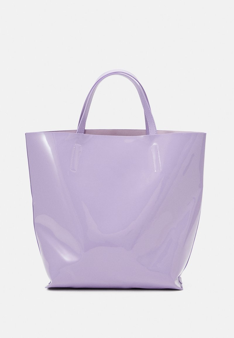 Sac cabas violet clair brillant avec deux poignées, présenté sur un fond uni gris clair.