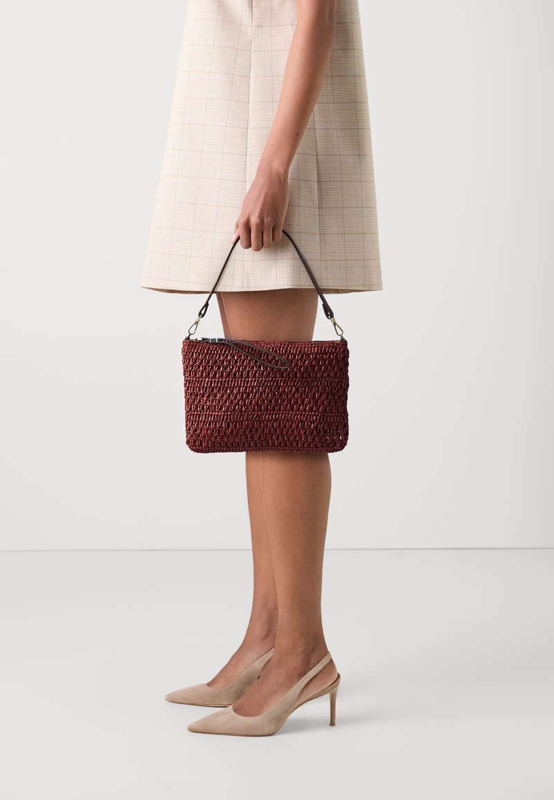 Borsa a mano intrecciata color bordeaux con superficie texturizzata e tracolla staccabile, insieme a un vestito a quadri beige e scarpe con tacco di colore nude.