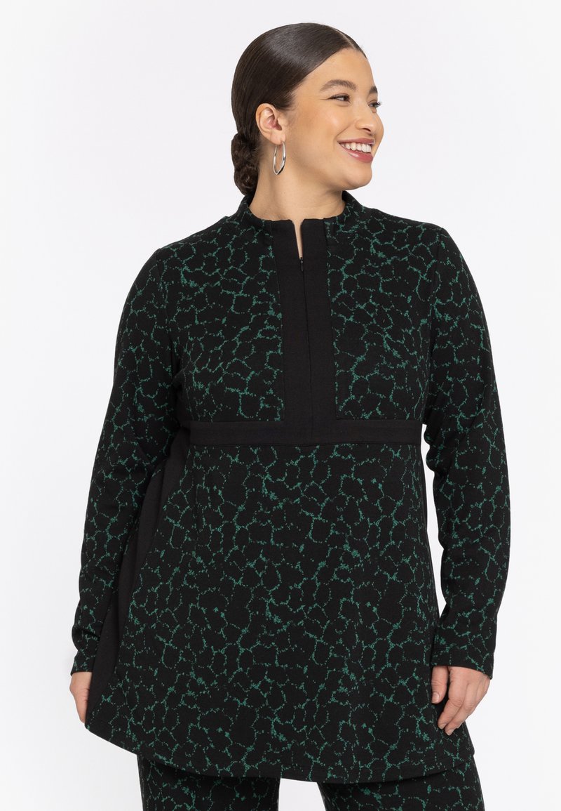 Tunique noire avec motif abstrait vert, dotée d'un col montant, de manches longues, d'une fermeture éclair et d'une taille ajustée. Texture lisse.