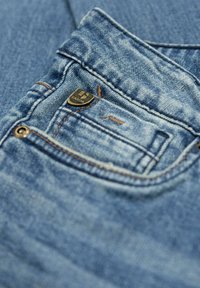 D žínové kalhoty s světlou modrou úpravou, s kontrastním švem, malou přední kapsou a kovovým logem značky na pásku.