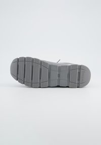 Szary bieżnik sneakersa z teksturowaną gumową powierzchnią, charakteryzującą się głębokimi rowkami i żebrami dla lepszej przyczepności. Minimalne oznakowanie po boku.