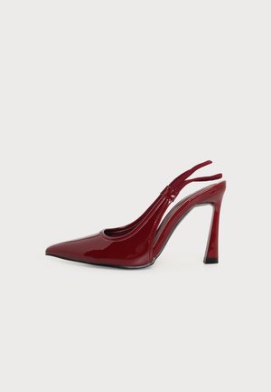 Červená lakovaná slingback lodička s vysokým podpätkom, hranatou špičkou a ihlovým podpätkom, zobrazená z profilu na čistom bielom pozadí.