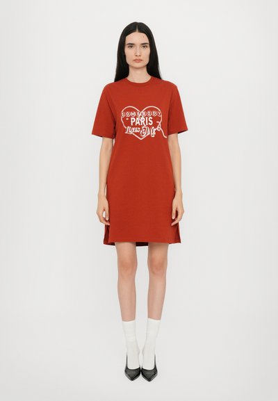 Abito in cotone rosso a t-shirt con scollatura rotonda, maniche corte e spacchi laterali. Presenta la scritta grafica bianca "Qualcuno a Parigi mi ama."