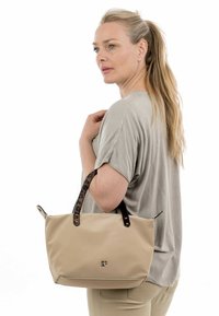 Borsa a spalla beige con manici leopardati, realizzata in materiale liscio, caratterizzata da un design semplice e un logo sul davanti.