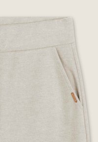 Pantalón jogger gris claro con textura acanalada, cintura elástica, bolsillo lateral y una pequeña etiqueta de cuero como detalle.