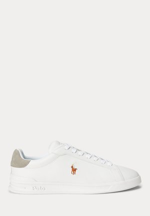 Białe niskie sneakersy z białymi sznurówkami, szarym zamszowym elementem na pięcie oraz wyszywanym brązowym logo polo gracza z boku.