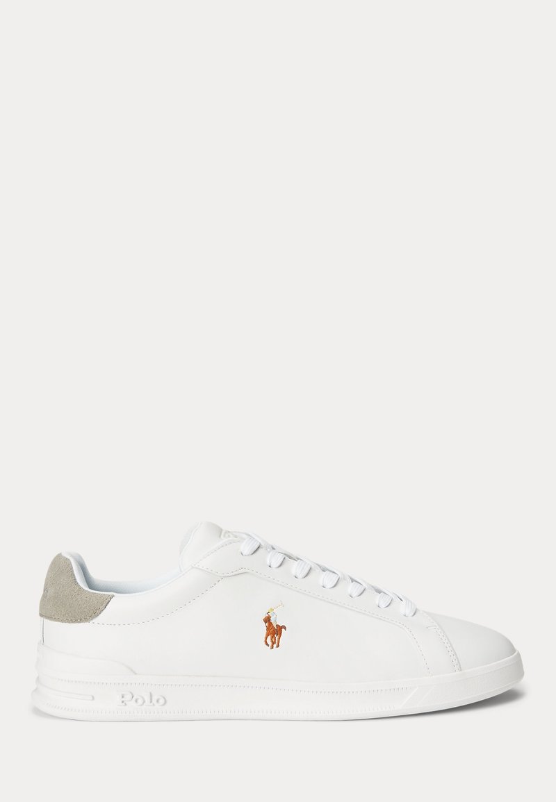 Baskets basses blanches avec lacets blancs, patch de talon en daim gris et logo brodé marron représentant un joueur de polo sur le côté.