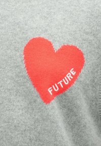 Țesătură gri tricotată cu o inimă mare roșie în centru, pe care este scris cu litere albe cuvântul „FUTURE”. Inima are un contur cusut.