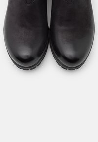 Czarne skórzane botki za kostkę o gładkim wykończeniu, zaokrąglonych noskach i minimalnym sprzęcie, z solidną podeszwą zapewniającą dobrą przyczepność.