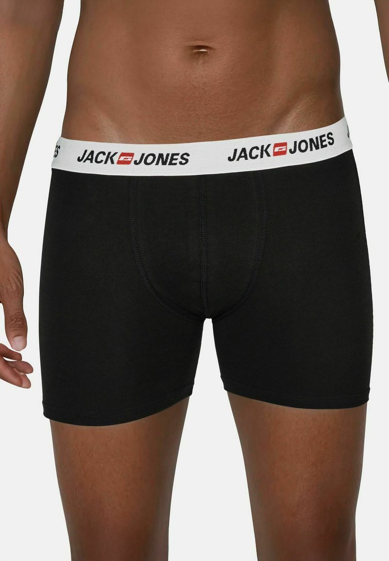 Black cotton boxer shorts with a white elastic waistband featuring "JACK & JONES" logo in black. Fitted design, smooth texture.