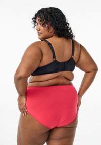 Black bra with adjustable straps and a hook closure, paired with red high-waisted underwear. Smooth fabric, with a minimalist design.