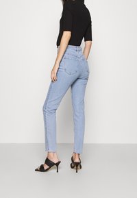 Vaaleansinisiä korkeavyötäröisiä farkkuja, joissa on slim fit ja viisi taskua. Yhdistettynä mustaan lyhythihaiseen puseroon ja mustiin korkokenkiin.