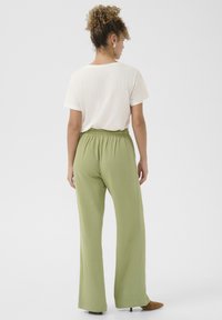 Lätta, löst sittande, pastellgröna byxor med elastisk midja; ihopparade med en kortärmad, vit överdel. Enkel design, mjuk textur.