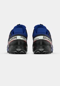 Salomon terepfutó cipők fekete és kék hálós felsőrésszel, megerősített sarokkal és texturált gumitalppal; hátul "SPEED" felirattal.