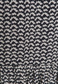 Schwarz- und beige Stoff mit einem Kaninchenmuster, das einen gerafften Saum und eine glatte Textur aufweist. Das Design zeigt ein sich wiederholendes Motiv.