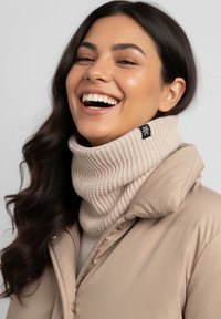 Beige knitted cowl neck warmer with a ribbed texture and a black logo tag, paired with a beige jacket. Circular shape for warmth.