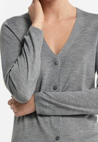 Šedý pletený kardigan s výstřihem do V, dlouhými rukávy a čtyřmi černými knoflíky vpředu. Měkká textura a přiléhavý střih.