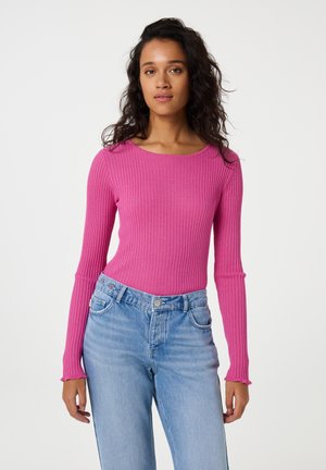 Langsleeve, geribbelde bodysuit in felroze, met een ronde halslijn en een aansluitende pasvorm, gecombineerd met lichtblauwe high-waisted jeans.