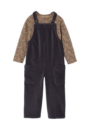 Corduroy overall in dark purple with adjustable straps, large front pockets, and a long-sleeved brown top with a zebra stripe pattern.